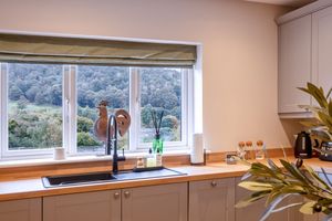 Modern kitchen with large window overlooking scenic countryside and natural light illuminating the countertops.