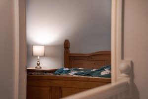 Cozy bedroom glimpse through doorway showing wooden headboard and bedside lamp.