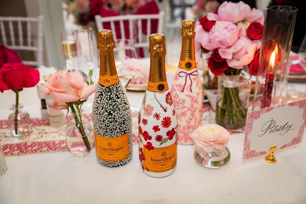 Elegant table setting with pink flowers and champagne bottles arranged for a celebration or wedding reception.