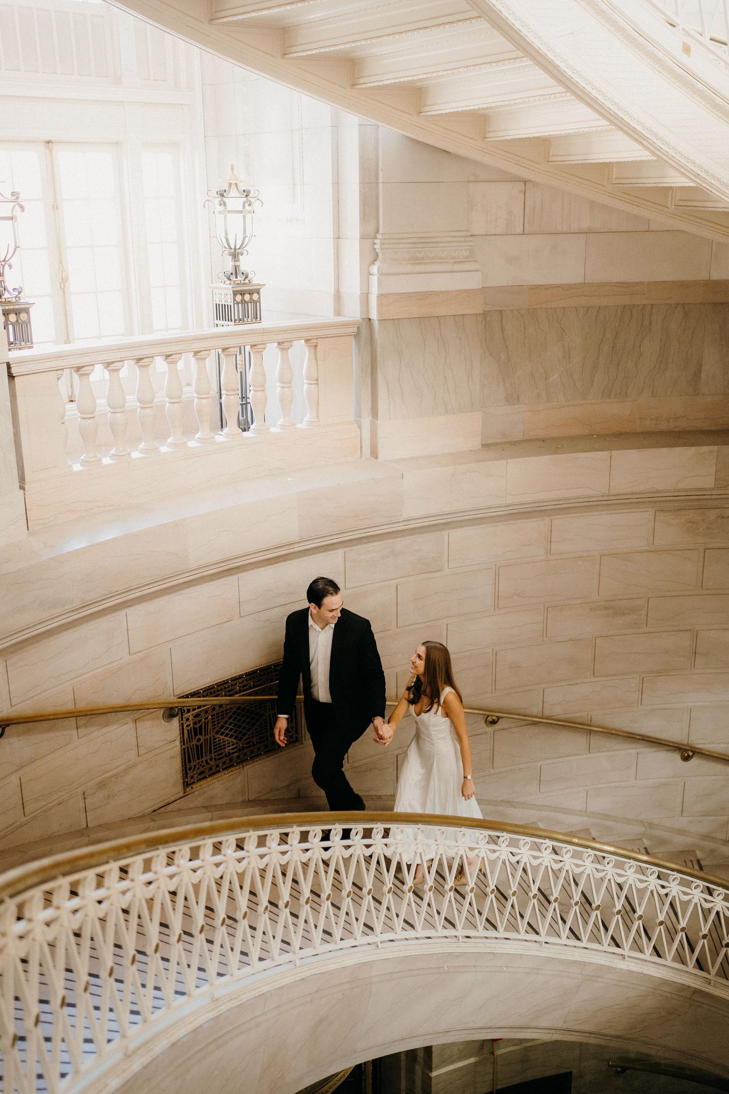 Three romantic moments captured on an elegant curved marble staircase with white architectural details.
