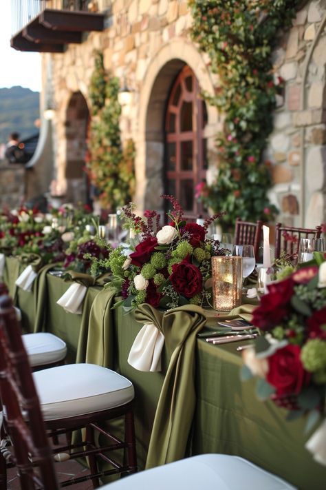 Elegant outdoor wedding reception table with olive green linens and burgundy floral centerpieces.