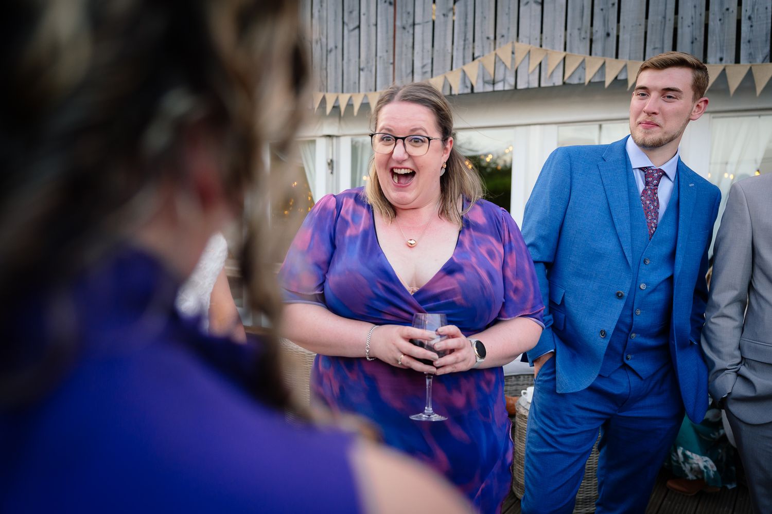 A couple in blue and purple attire share candid laughing moments during a photo session.