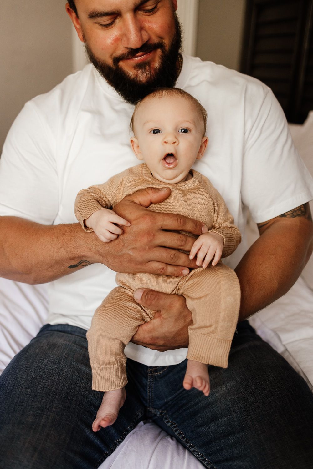 A dad smiles at his baby in his arms