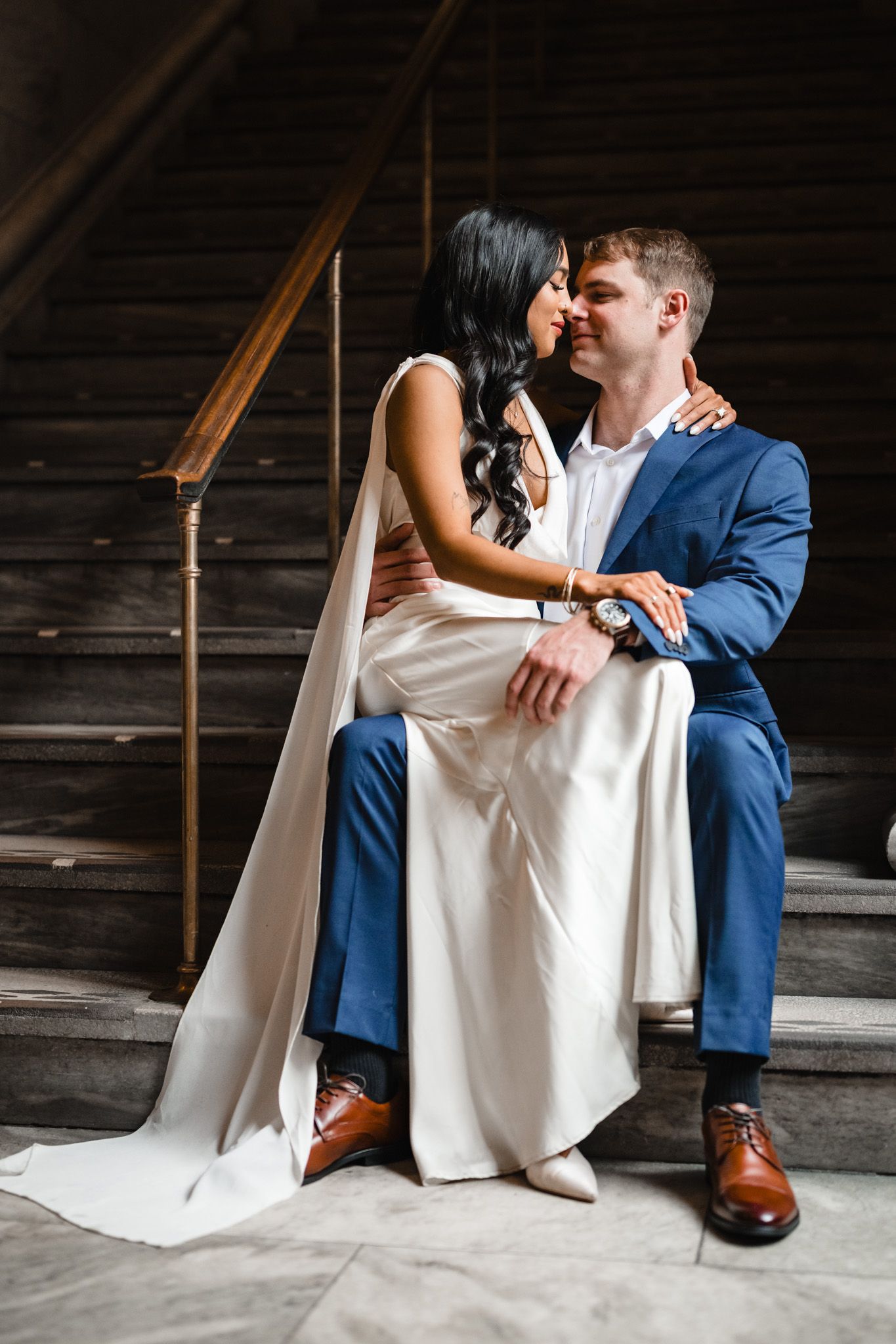 Intimate seated portrait on marble steps showcasing wedding attire details.