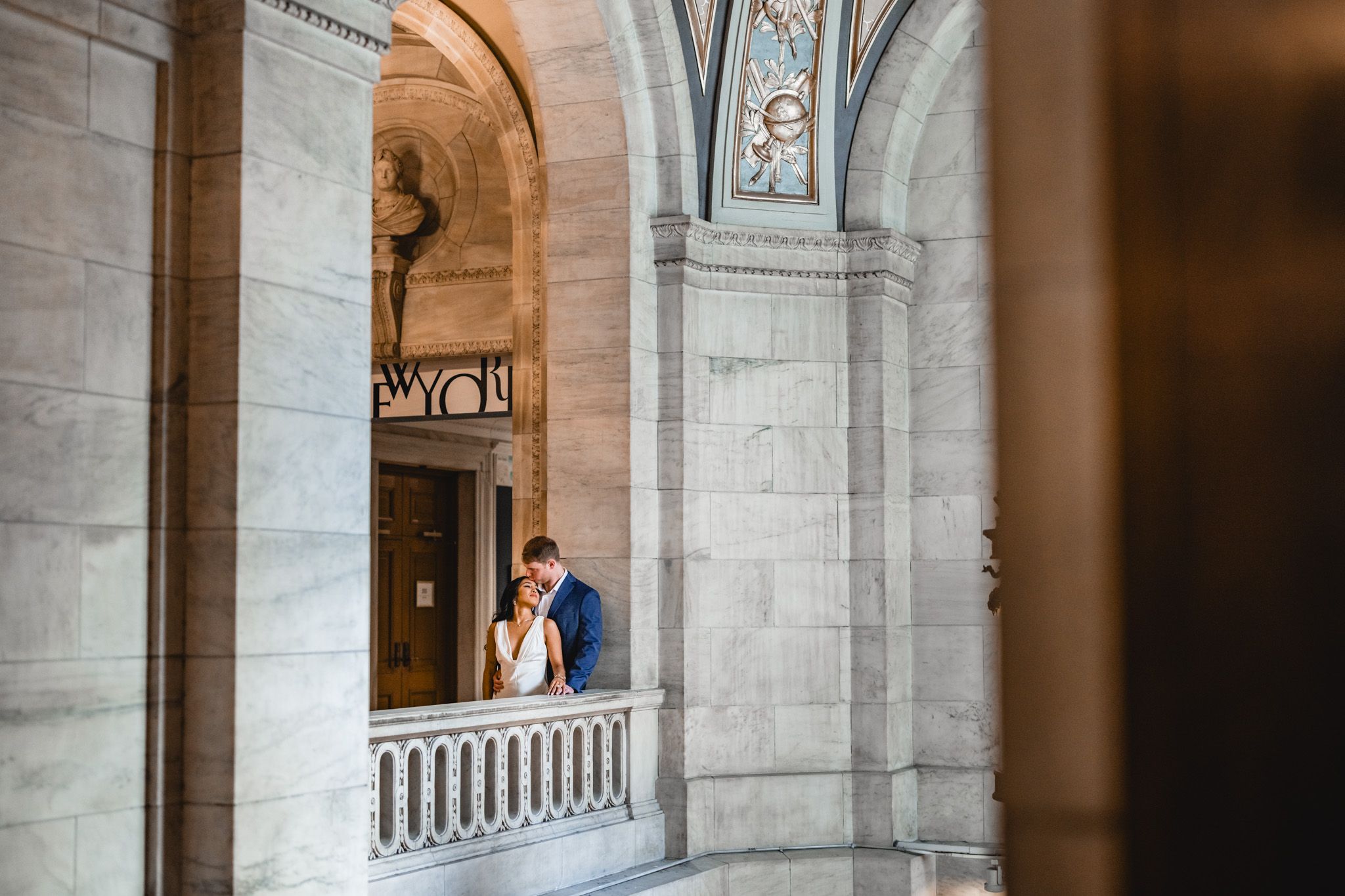 Dramatic architectural framing of couple through stone arches and columns.