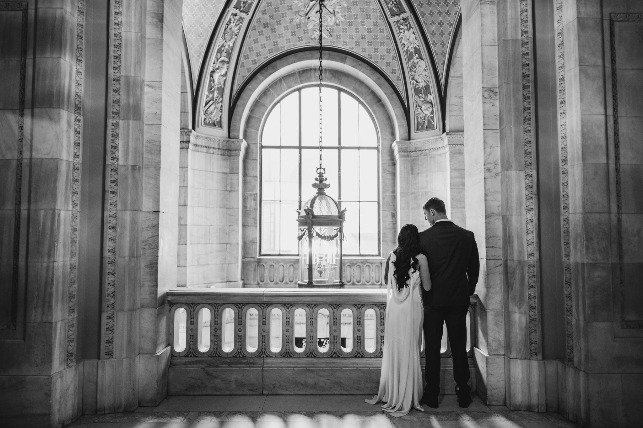 Romantic silhouettes in grand historic building with arched windows and natural light.