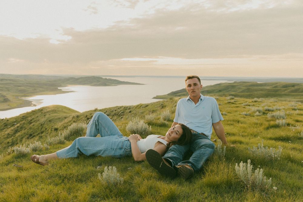 Person relaxing in camping tent overlooking scenic coastal landscape at sunset.