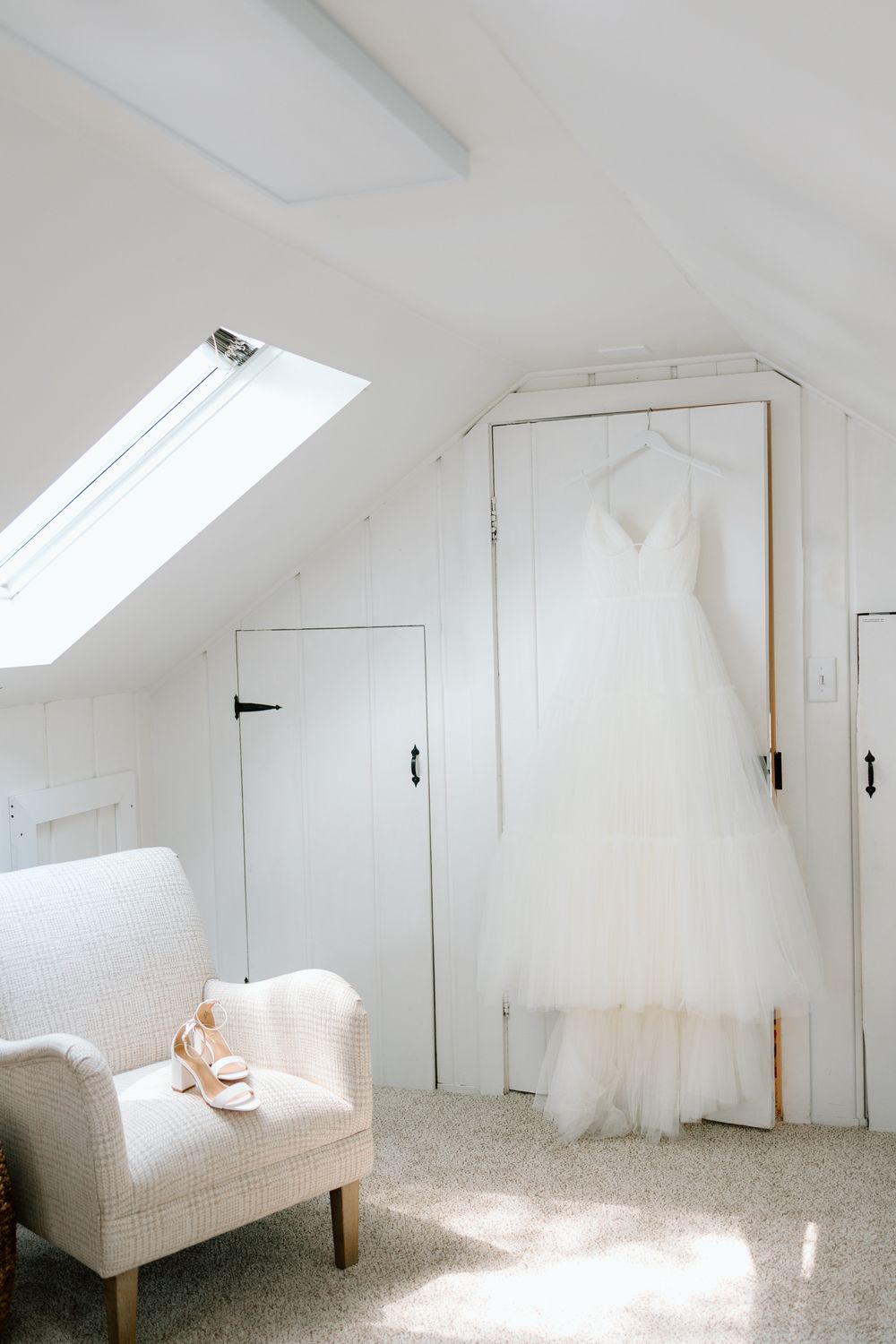 Bright white attic room with skylight windows and a minimalist bed setup in natural sunlight.