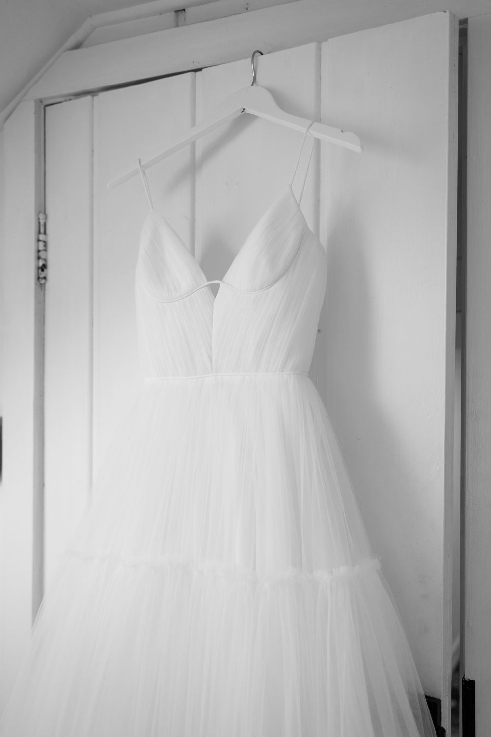 White wedding dresses hanging on display in a bridal boutique with natural lighting.
