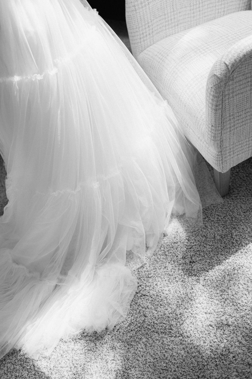 Flowing white wedding dress veil draped elegantly across a textured carpet floor.