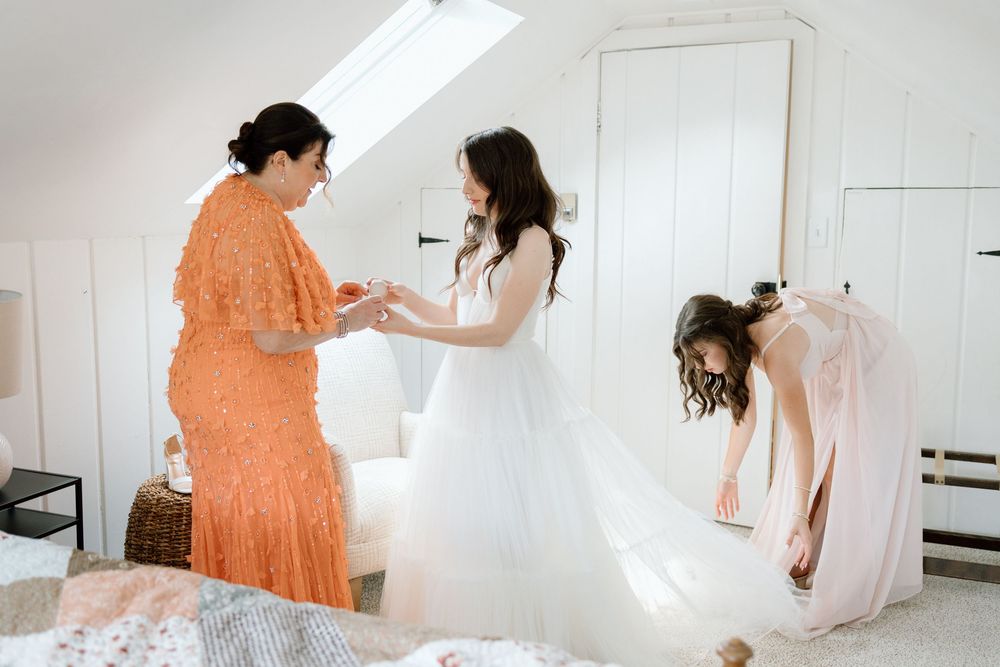 A woman in a flowing orange dress spins and dances in a bright white room with natural lighting from above.