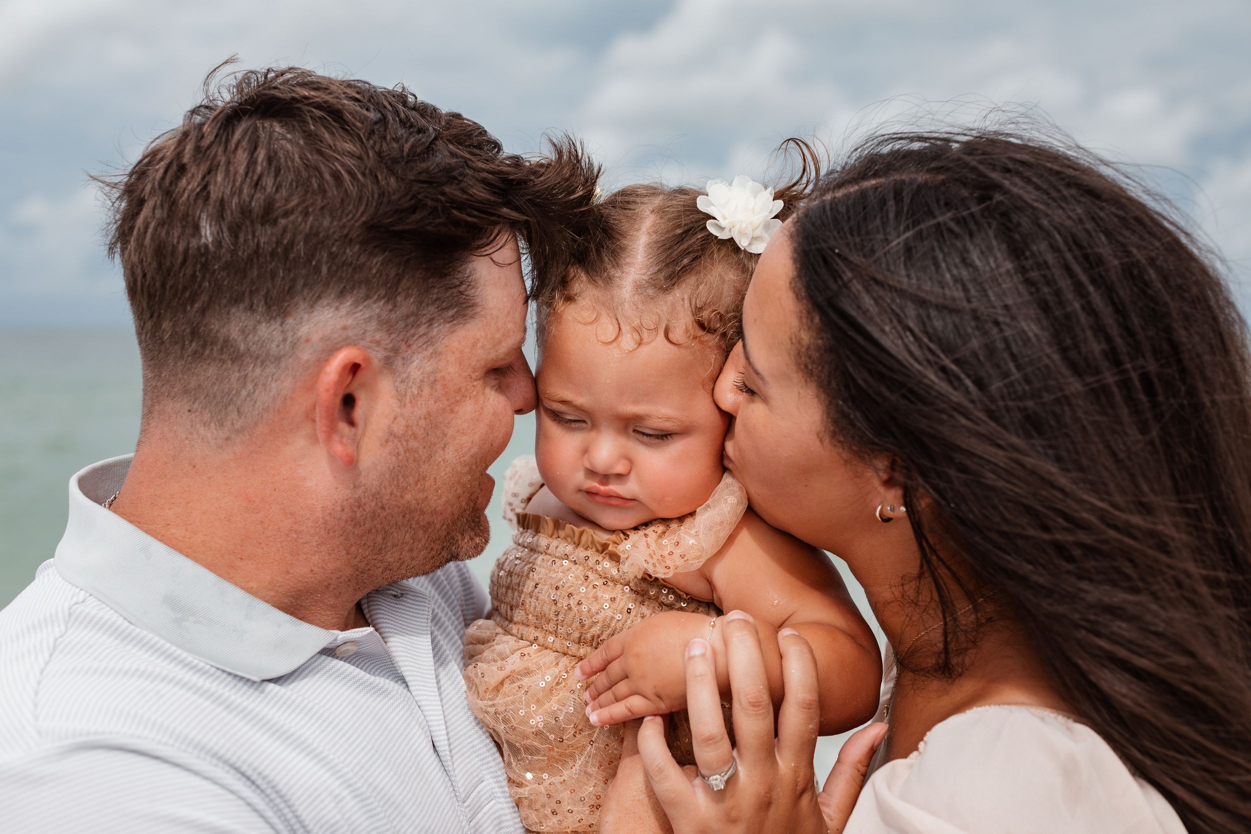 Mother and Father holding daughter on the beach in St. Petersburg, Florida.