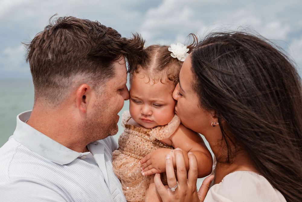 Mother and Father holding daughter on the beach in St. Petersburg, Florida.