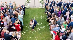 Wedding guests throw white flower petals as they celebrate during an outdoor garden ceremony.