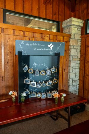 Rustic wooden wall display with chalkboard panels and string lights holding vintage photos and decorative elements.