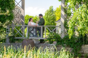 Bride and groom share a romantic moment on a garden pergola surrounded by lush green foliage on their wedding day.