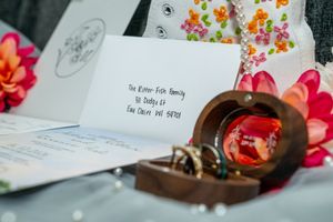 Elegant wedding invitation addressed to the Ritter Fish family beside a wooden ring box with amber glass lid.