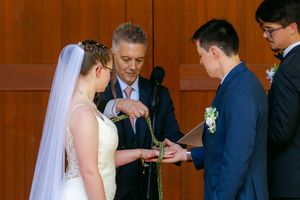 Bride and groom exchanging rings during wedding ceremony with officiant at altar.