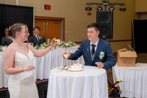 Bride and groom clinking champagne glasses at wedding reception table in elegant banquet hall.