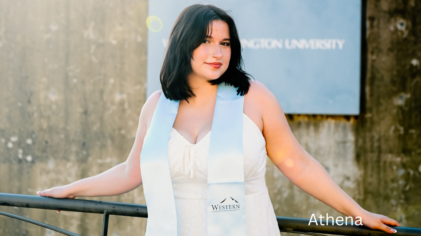 Person in white dress poses against concrete wall near Viking Union sign.