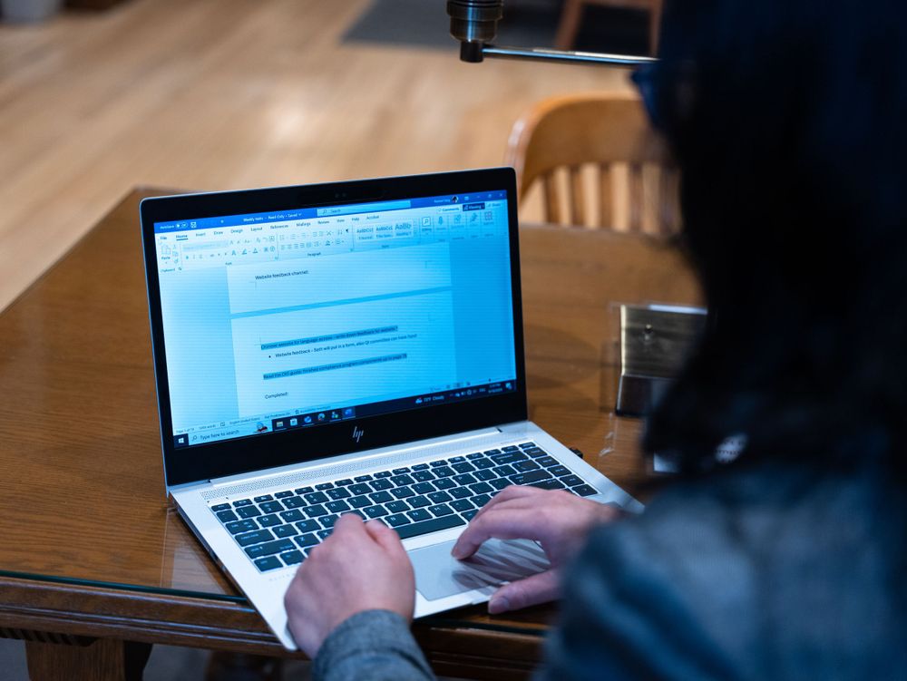A close-up of hands typing on a silver laptop keyboard.