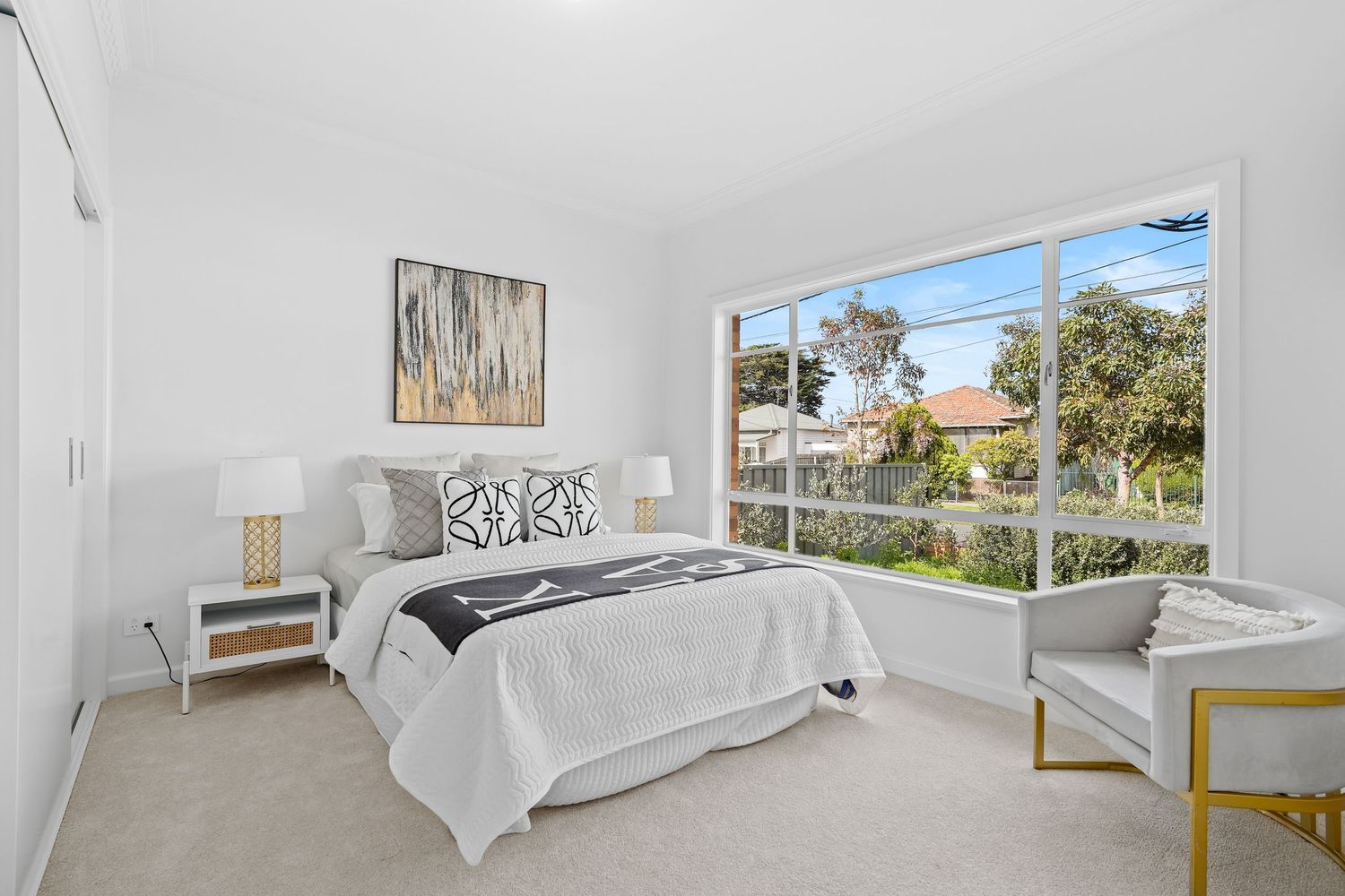 Bright bedroom with white bedding, window views and contemporary wall art.