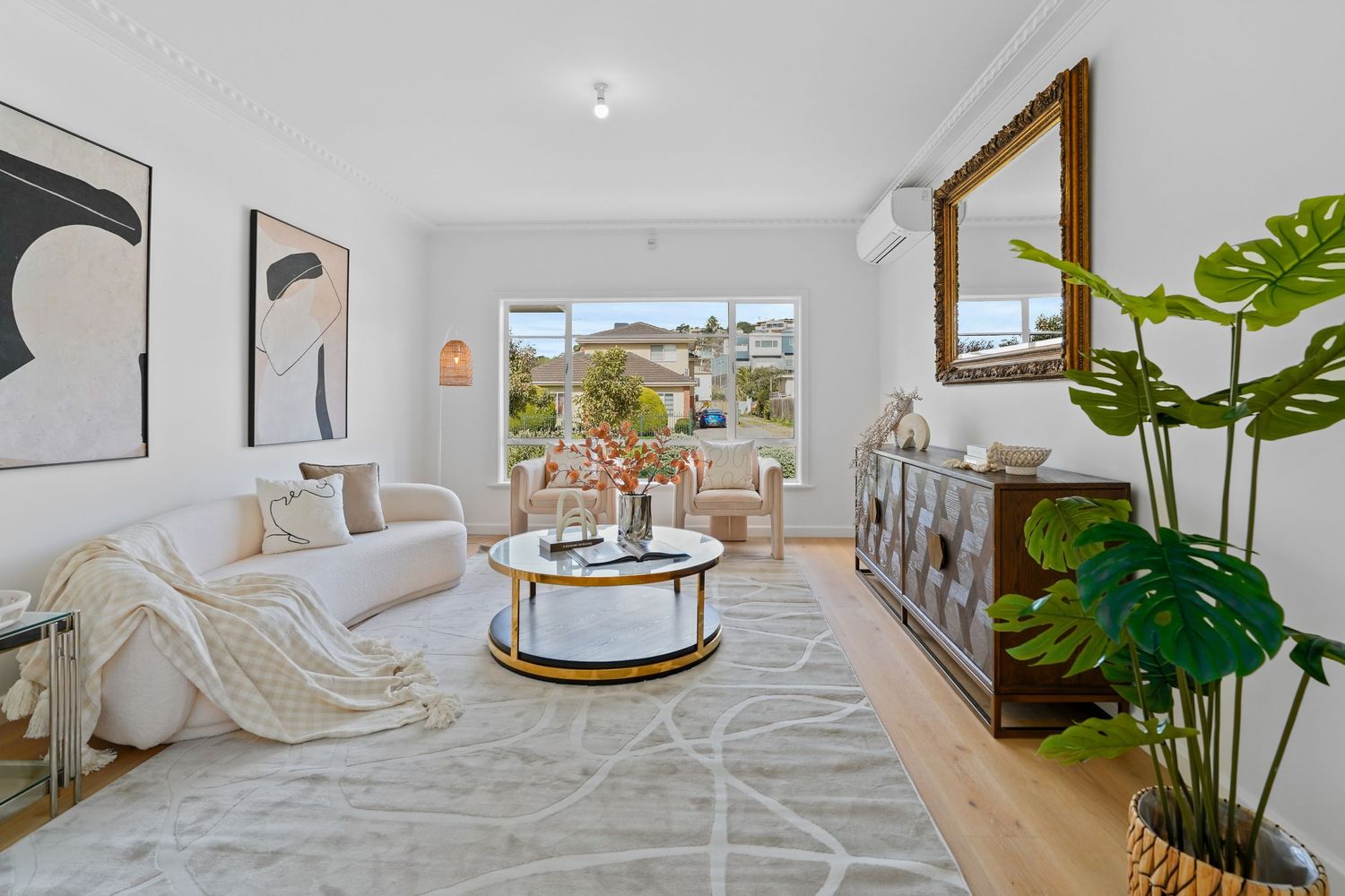 Contemporary living room with white furniture, round coffee table and indoor plant.