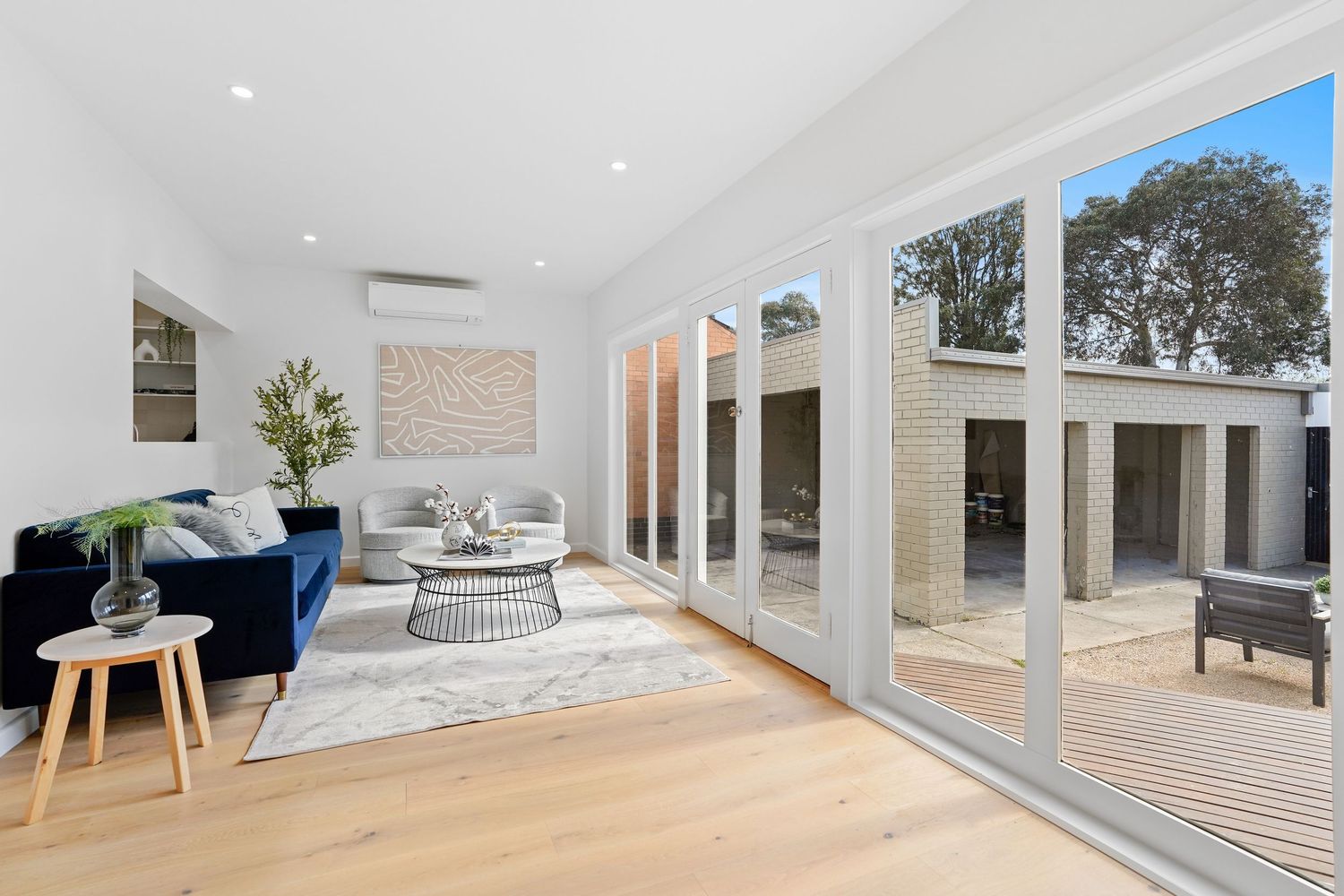 Bright living room with blue sofa and glass sliding doors opening to outdoor deck.