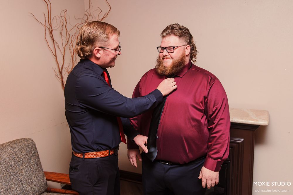 Two people in formal attire share a lighthearted moment while conversing in an indoor setting.