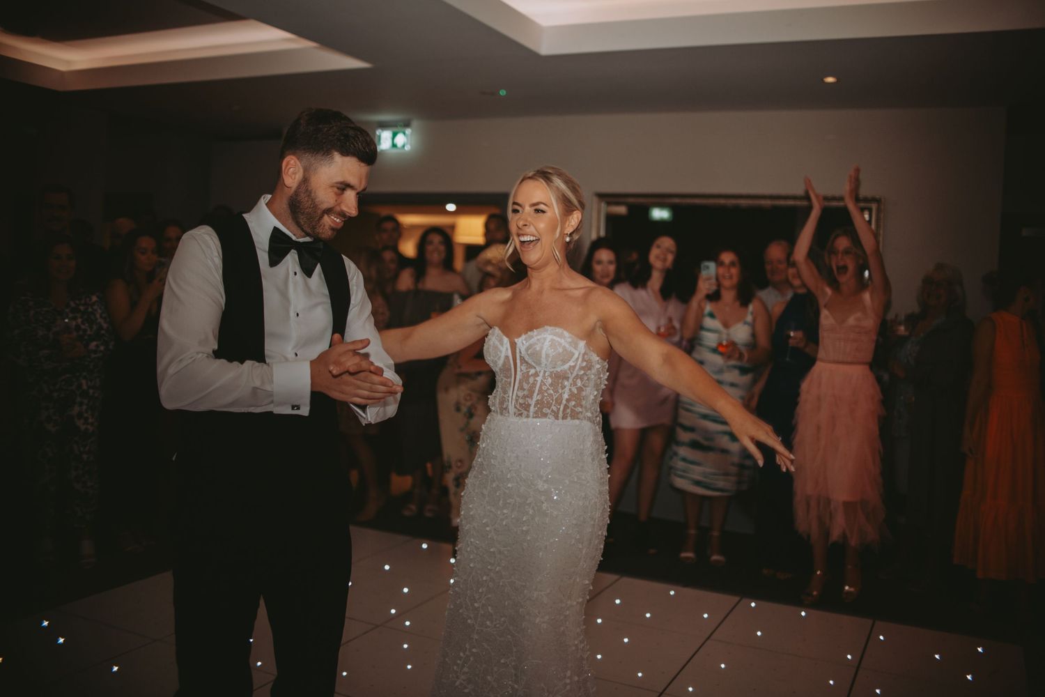 Couples dance together during a romantic evening wedding reception with mood lighting.