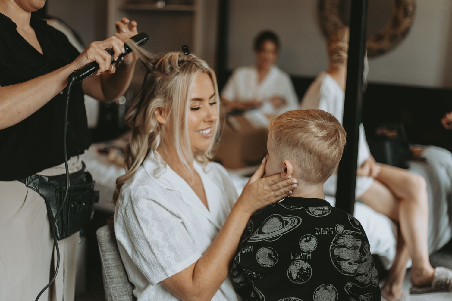 Wedding morning preparations with makeup artists working in natural light.