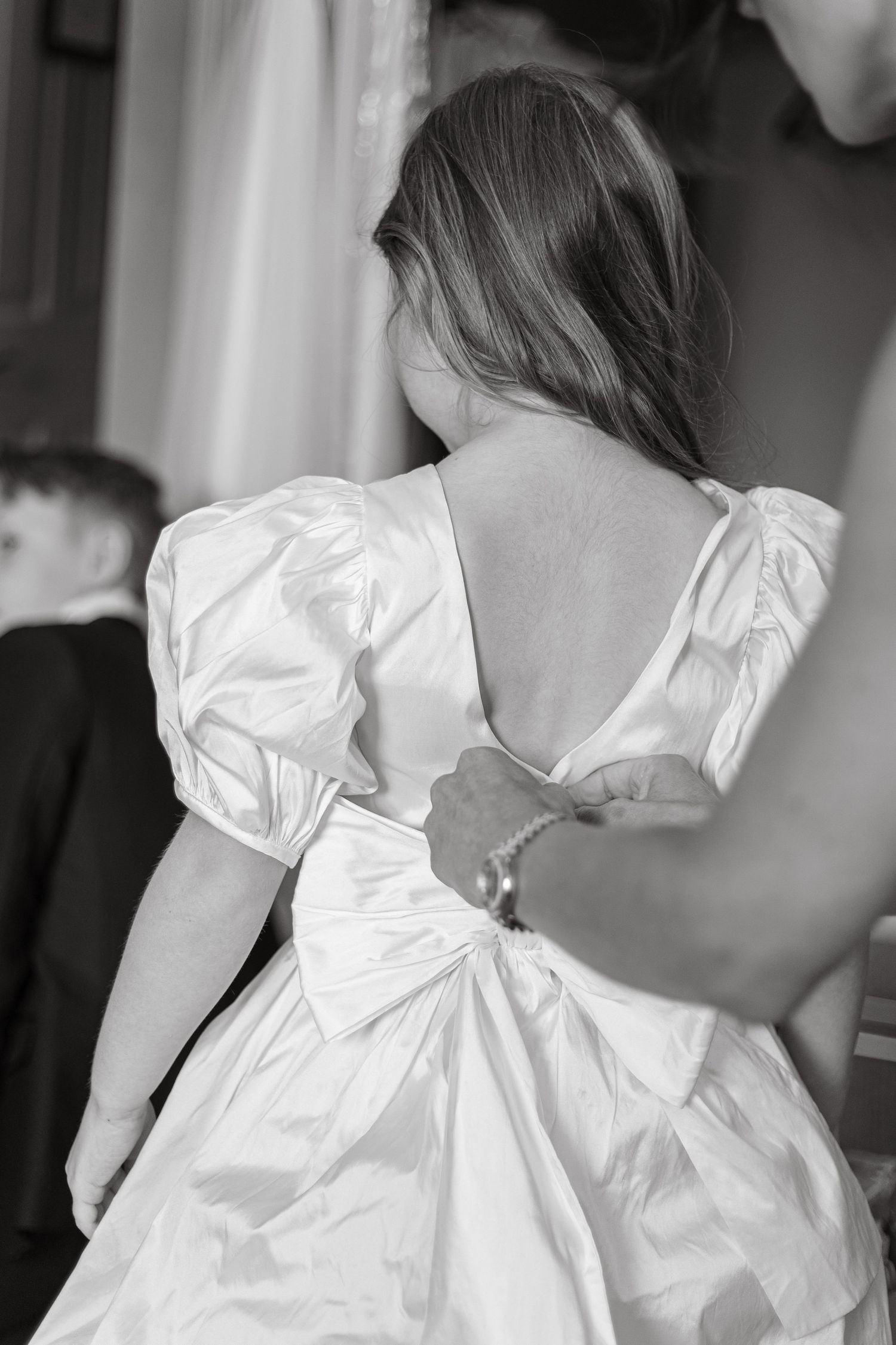 Back view of white dress with puff sleeves being buttoned up.