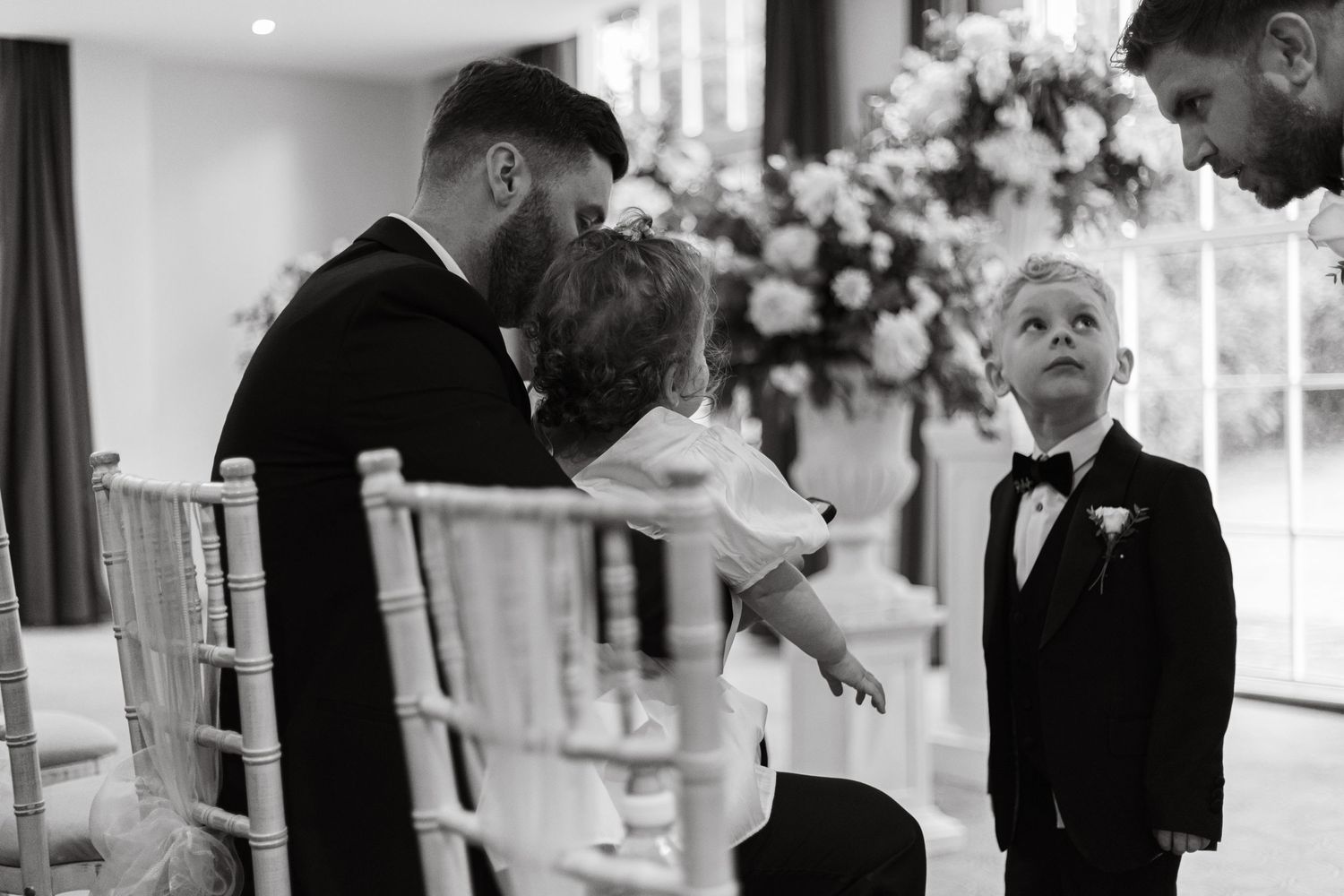 Wedding guests share emotional moments during an indoor ceremony with elegant floral decorations.