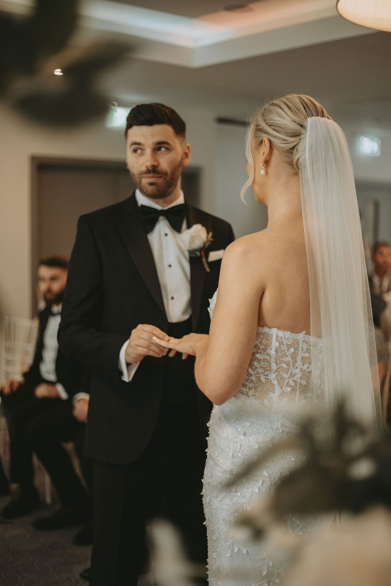Intimate wedding ceremony moments captured in warm lighting with elegant bridal details.