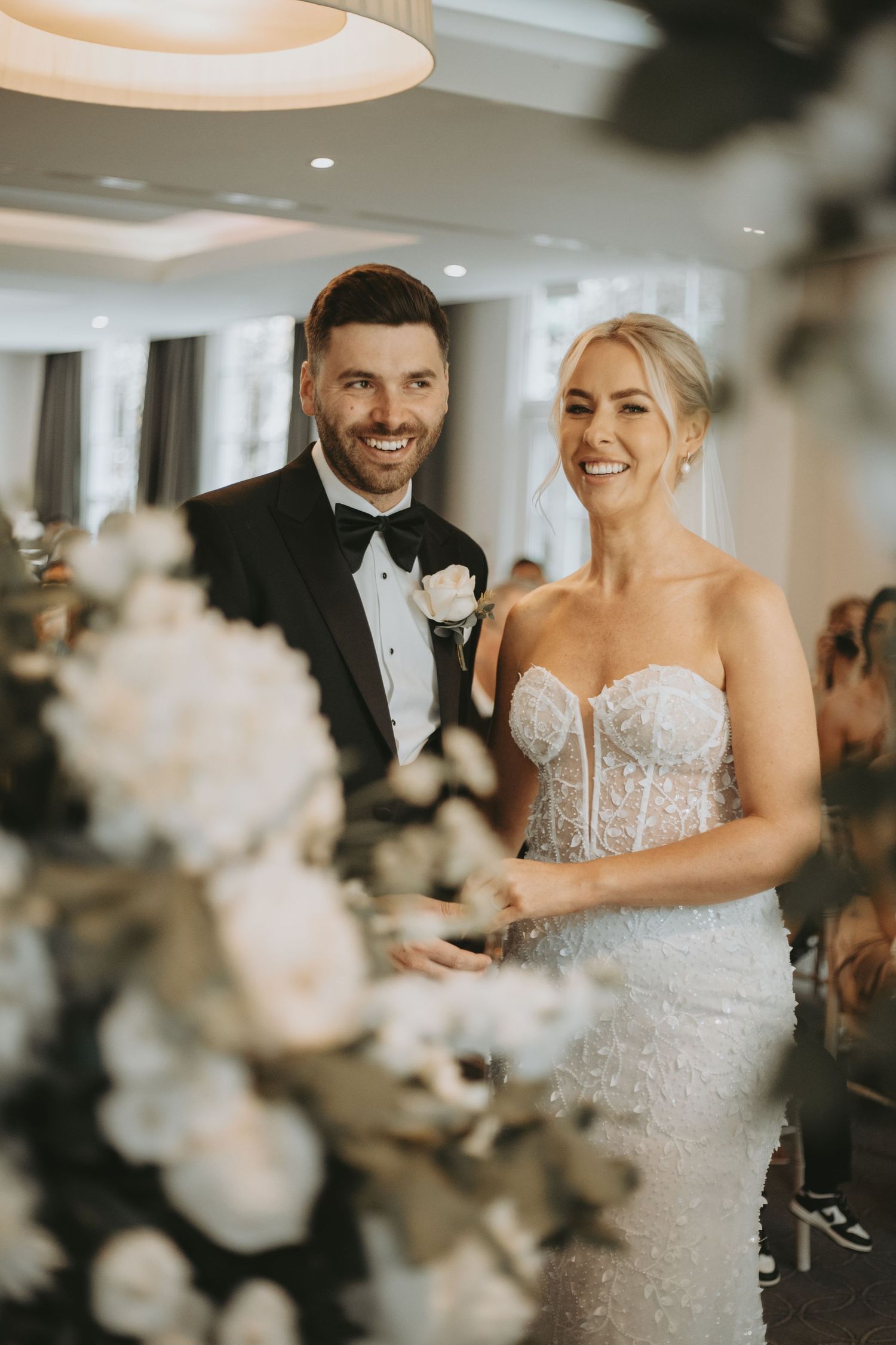 A joyful couple embraces during their first dance at a wedding reception with soft lighting.