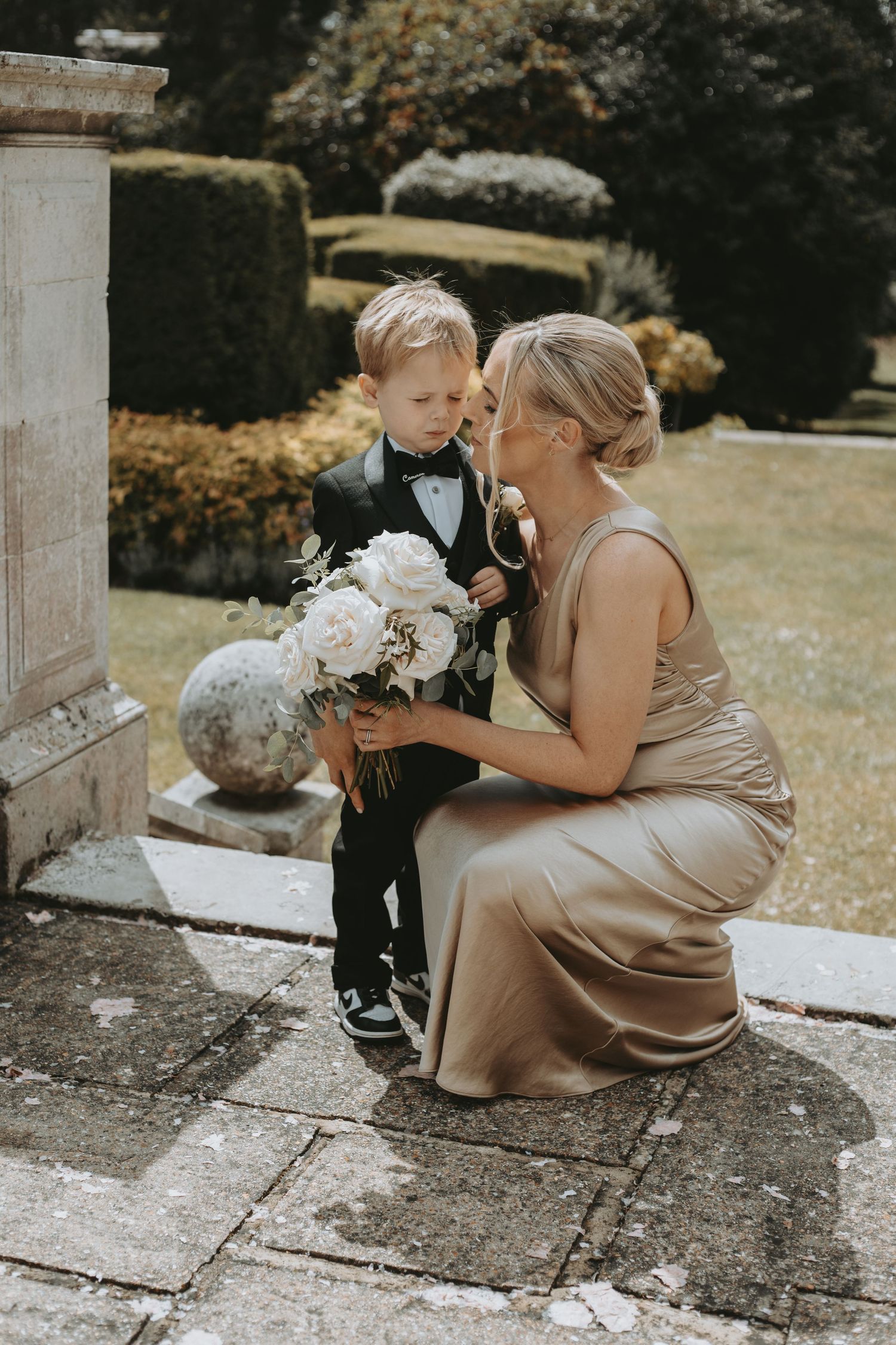 A sweet moment between a young ring bearer and wedding party member on stone steps.
