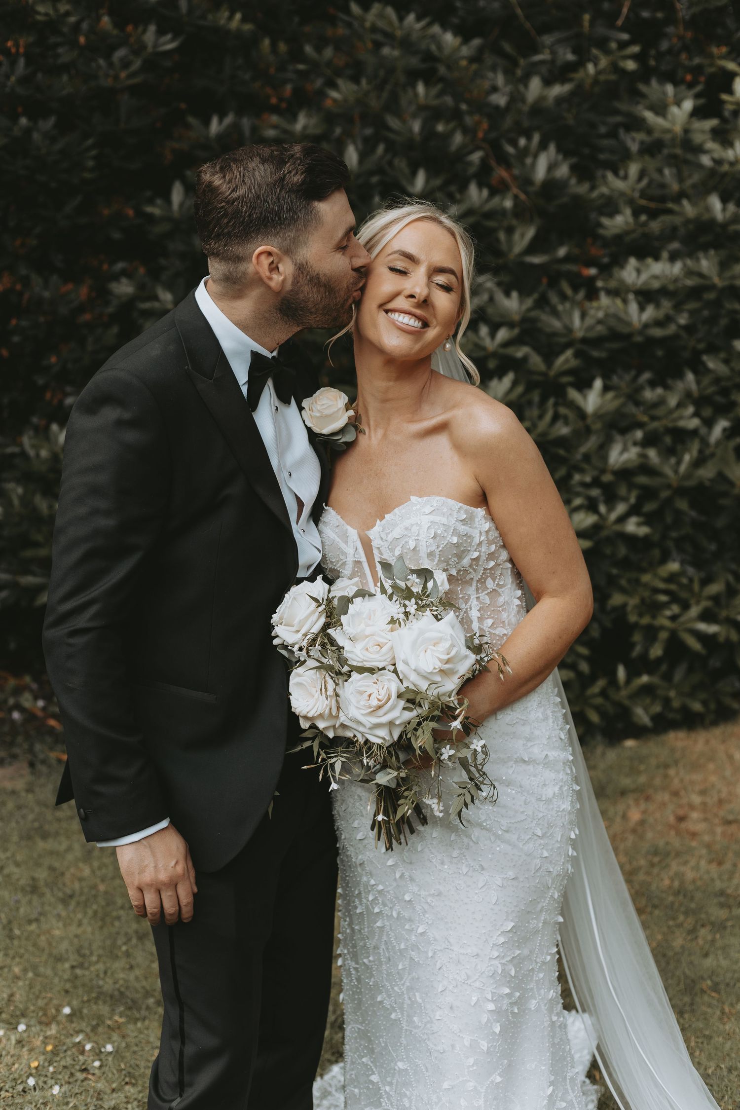 Romantic wedding portraits captured in a garden setting with lush greenery backdrop.