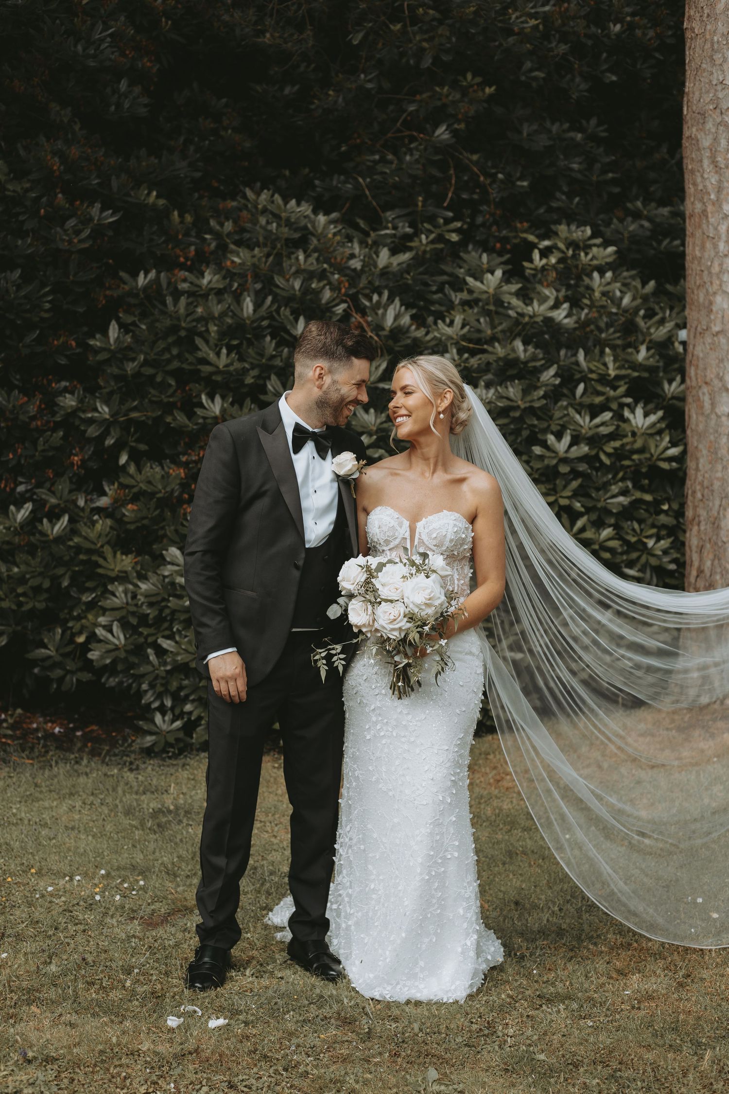 A couple shares intimate moments during their wedding photoshoot in a garden setting.