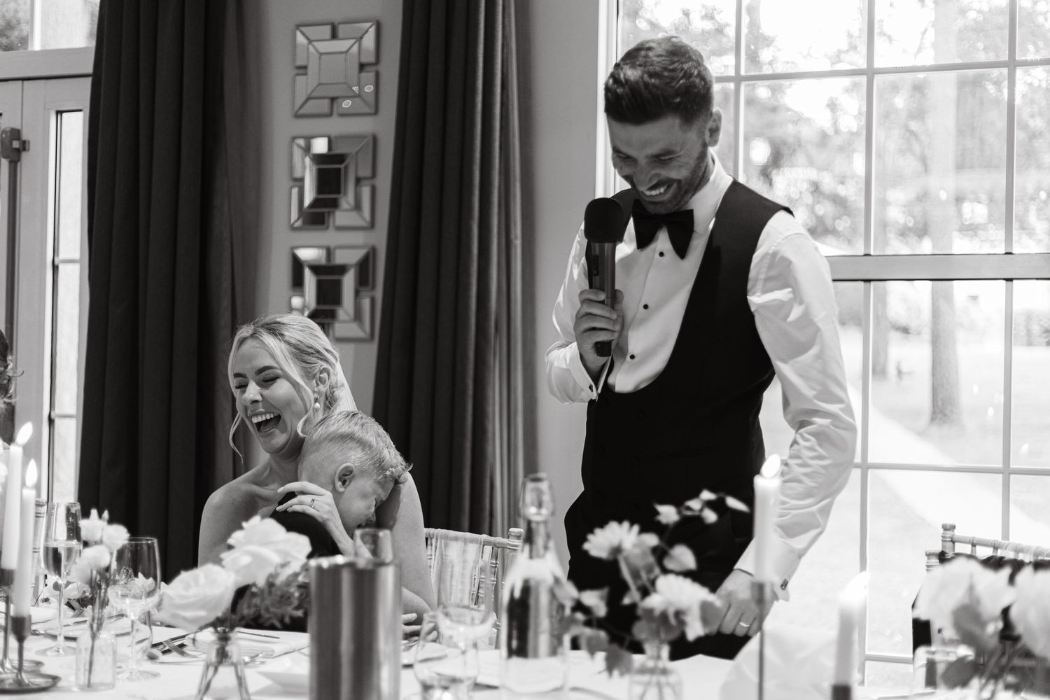 A formal wedding reception venue decorated with elegant curtains and natural lighting through tall windows.