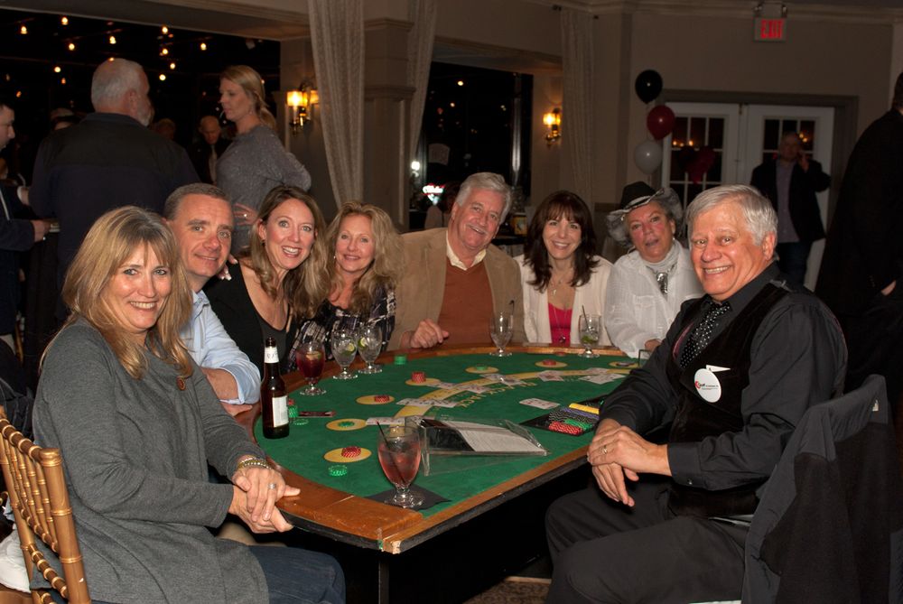A group of people gathered around a green gaming table at a social event.
