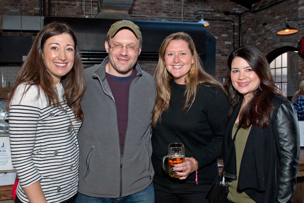 Four friends pose together at an industrial-style venue during a social gathering.