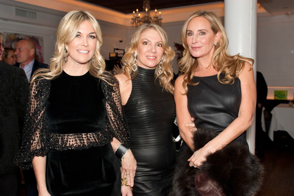 Three women in black formal dresses posing at an elegant event.