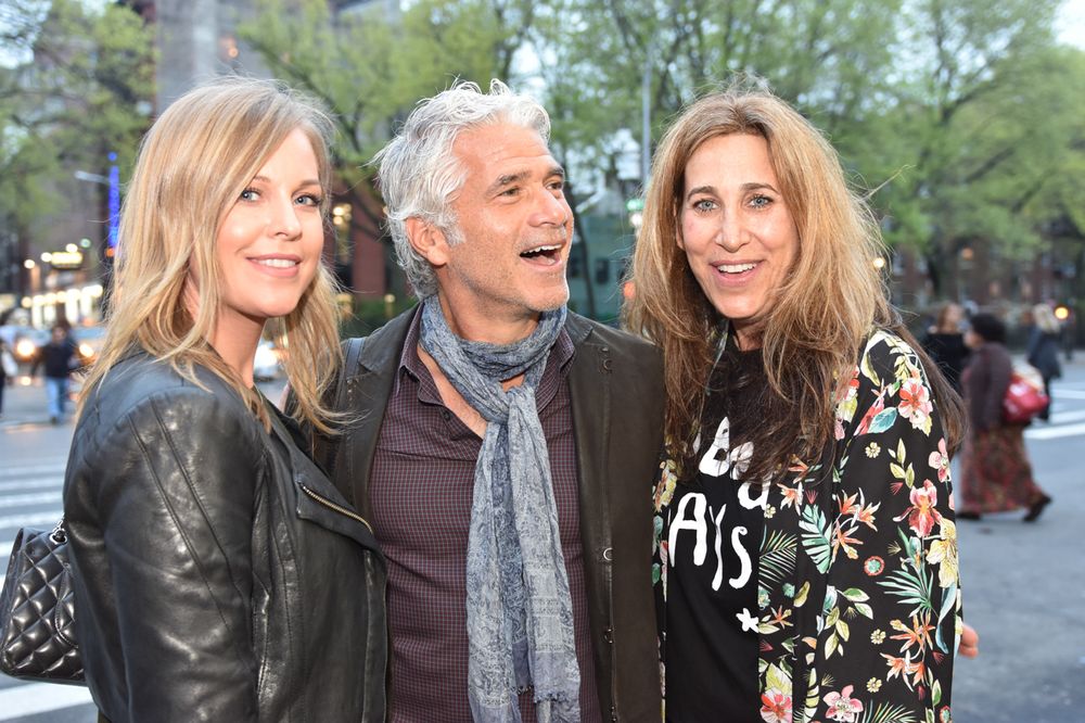Three people smile together outdoors on a spring day in the city.