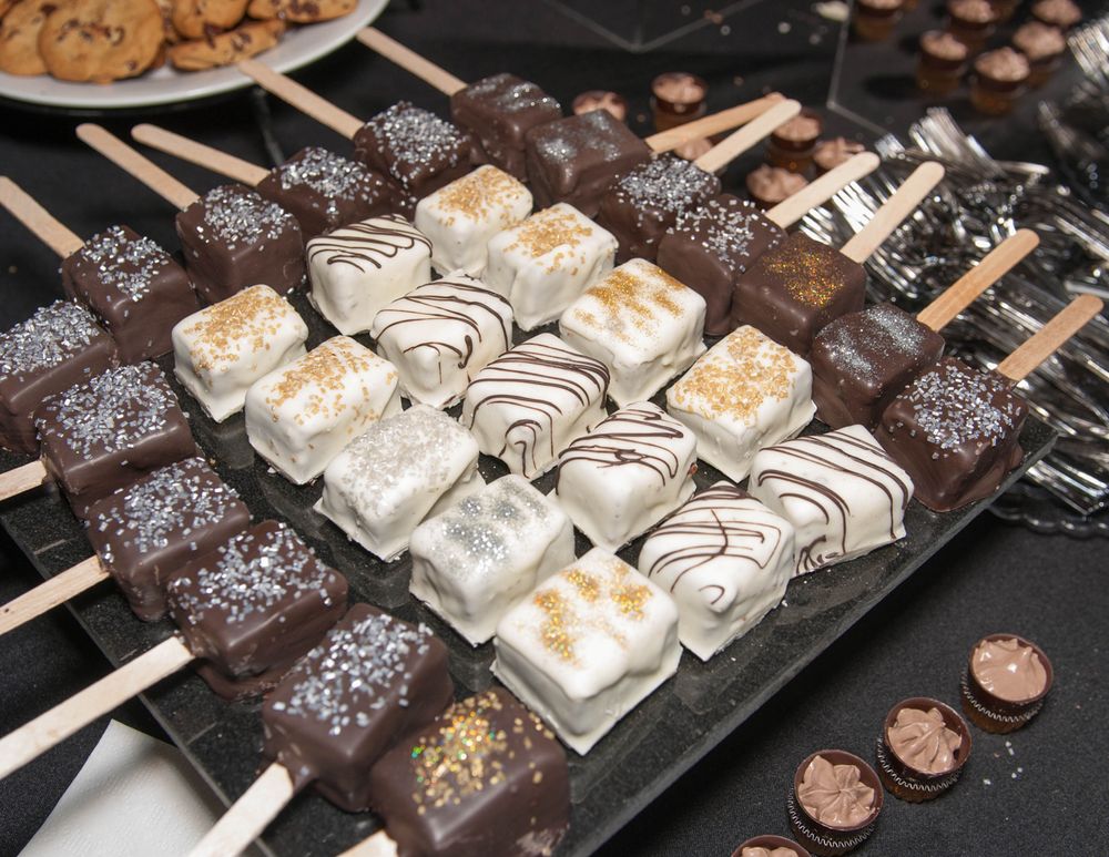 Display of chocolate covered desserts on sticks arranged on a serving platter.