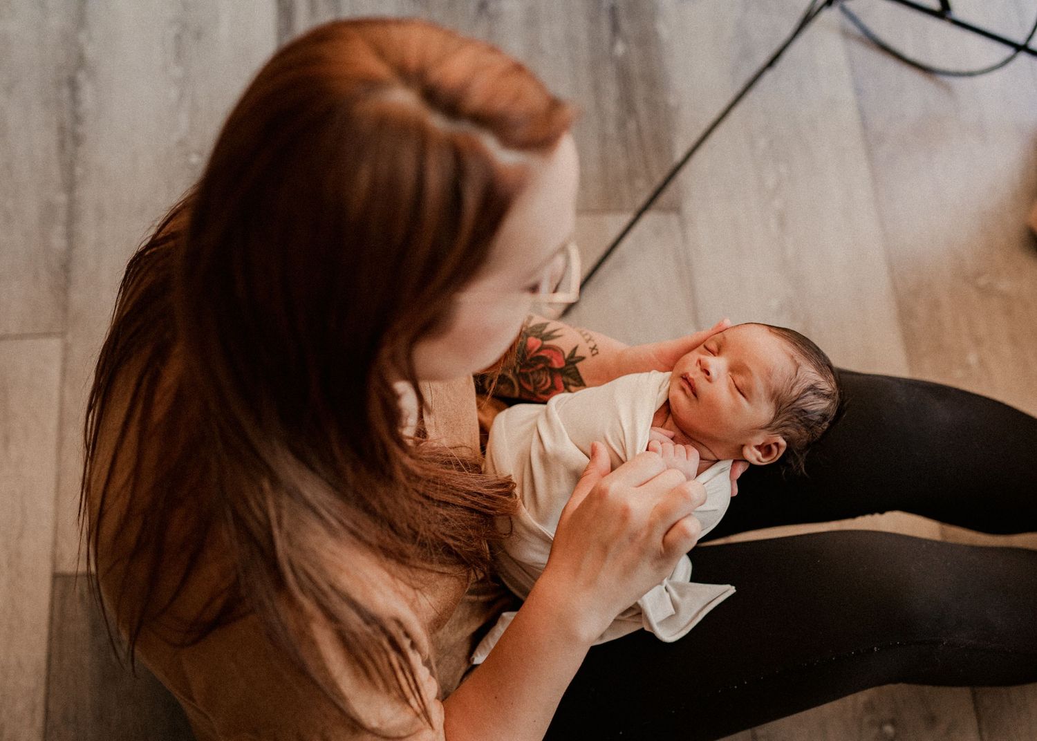 A tender moment between a caregiver and a newborn baby in a warm, intimate indoor setting. Michigan Newborn Baby Photographer, Highland MI