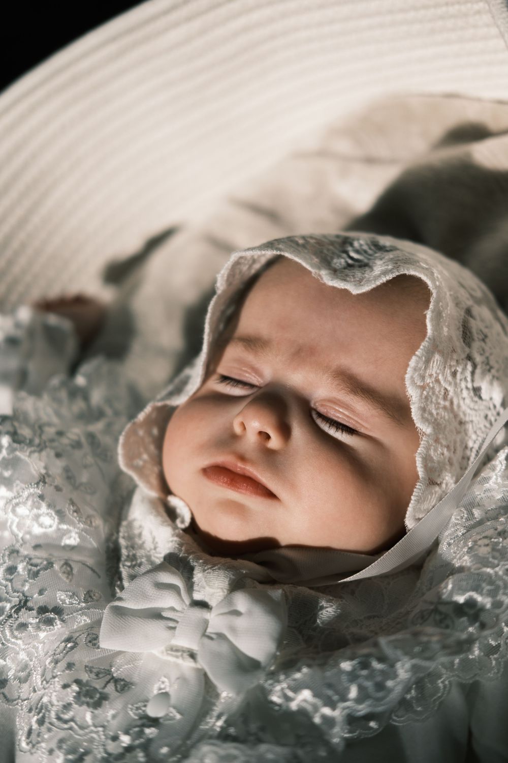 Sleeping baby portrait session in a white lace bonnet and outfit