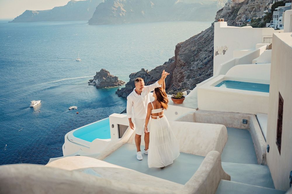 A couple enjoying the stunning views of Santorini's caldera with white buildings and infinity pools.