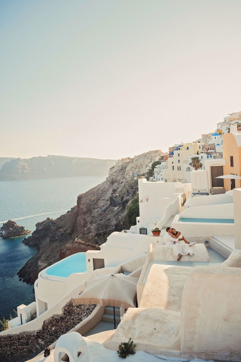 Classic Santorini landscape with white buildings cascading down the cliffs above the blue Aegean Sea.