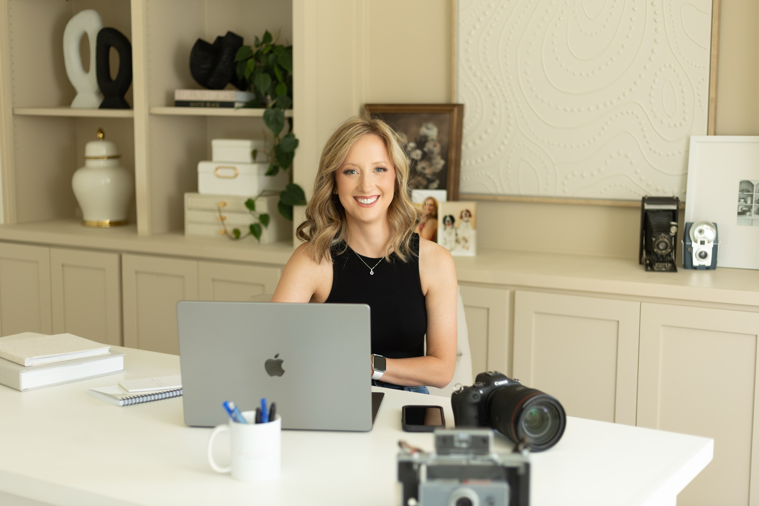 Professional photographing setup with laptop and camera in home office with built-in shelving.