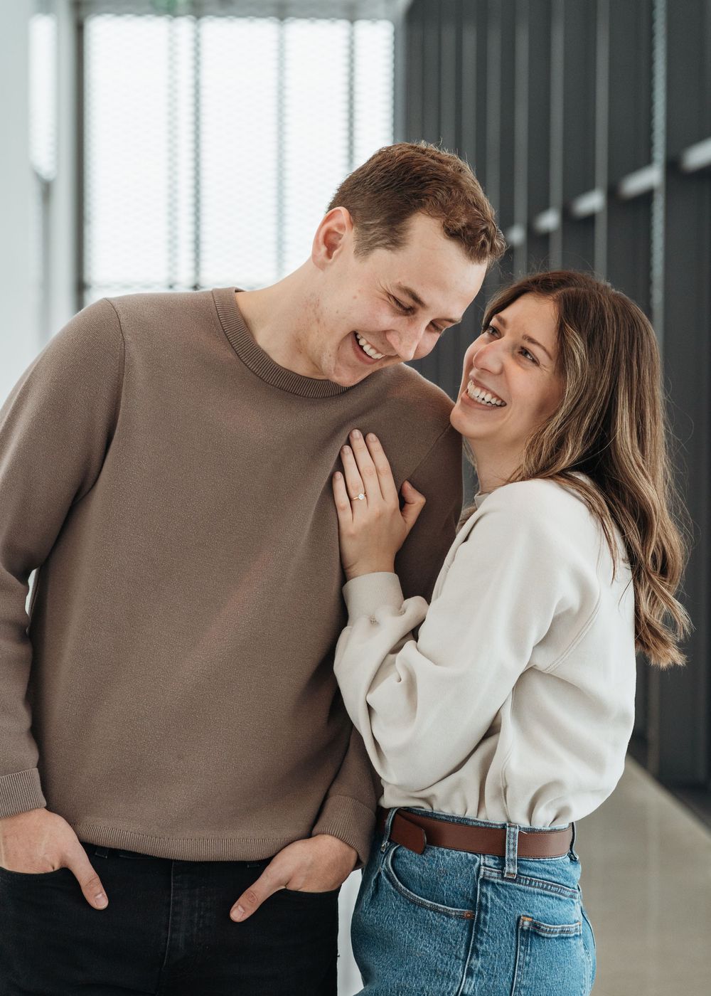 Happy couple in casual sweaters share joyful moment in modern interior setting.